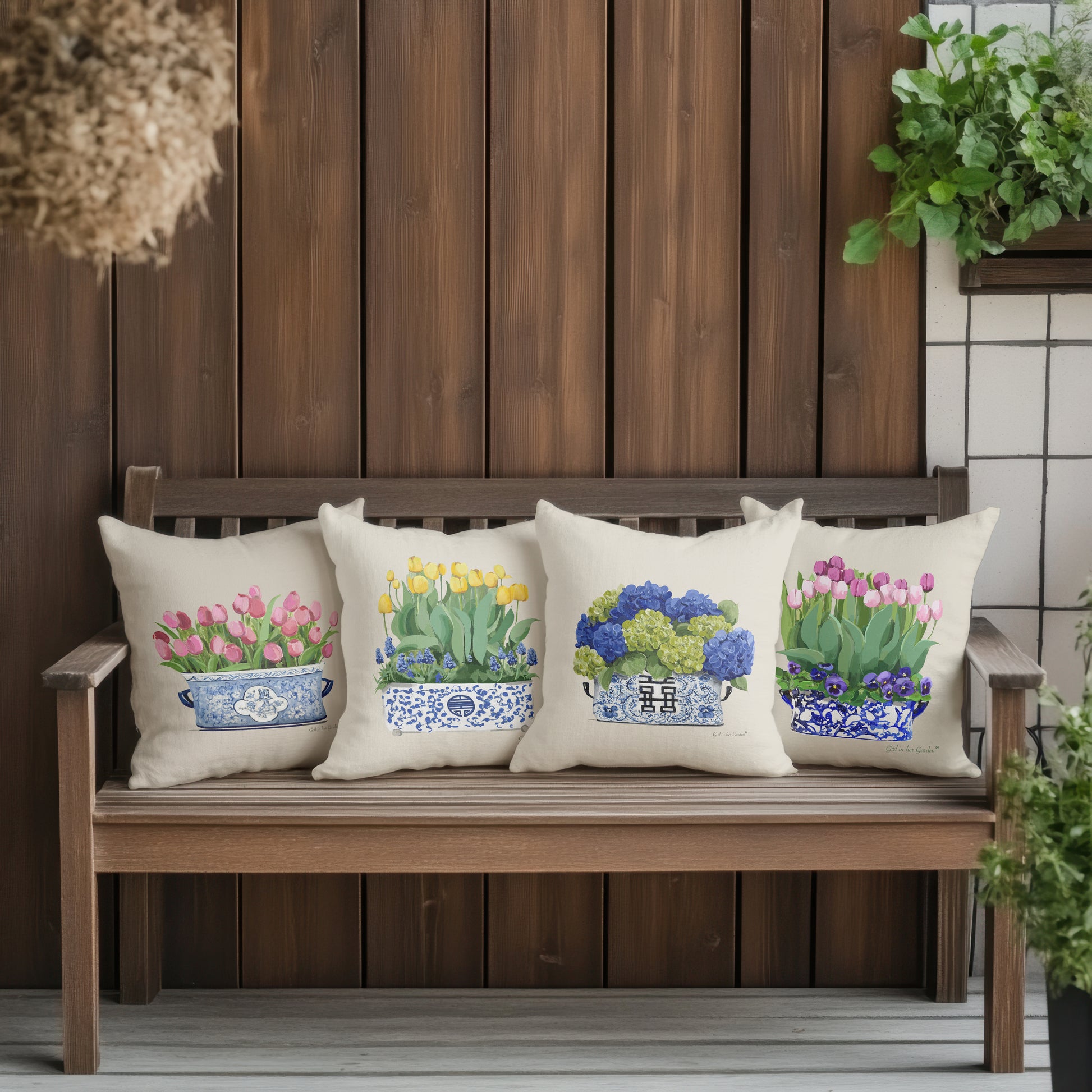 Four decorative pillows with floral designs on a wooden bench against a wooden wall.