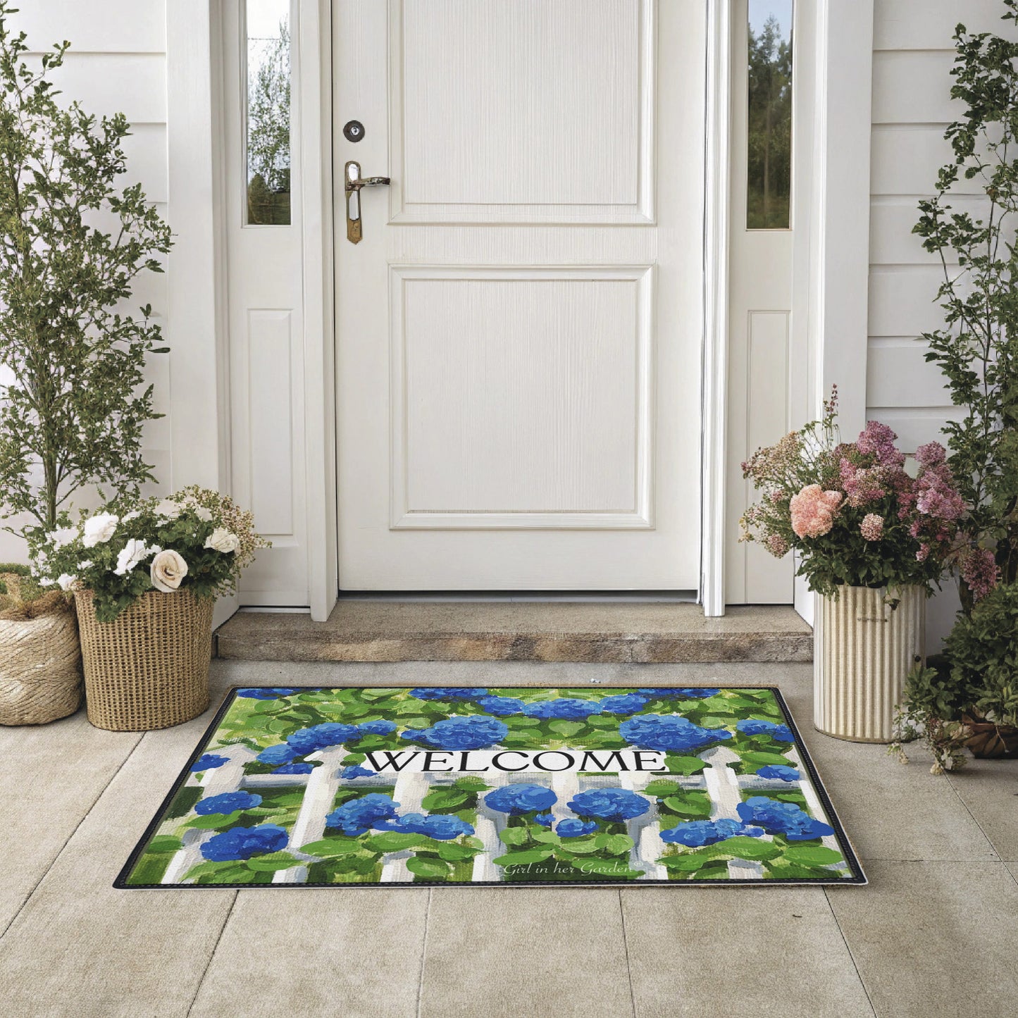 Decorative doormat with floral design and 'Welcome' text in front of a white door.