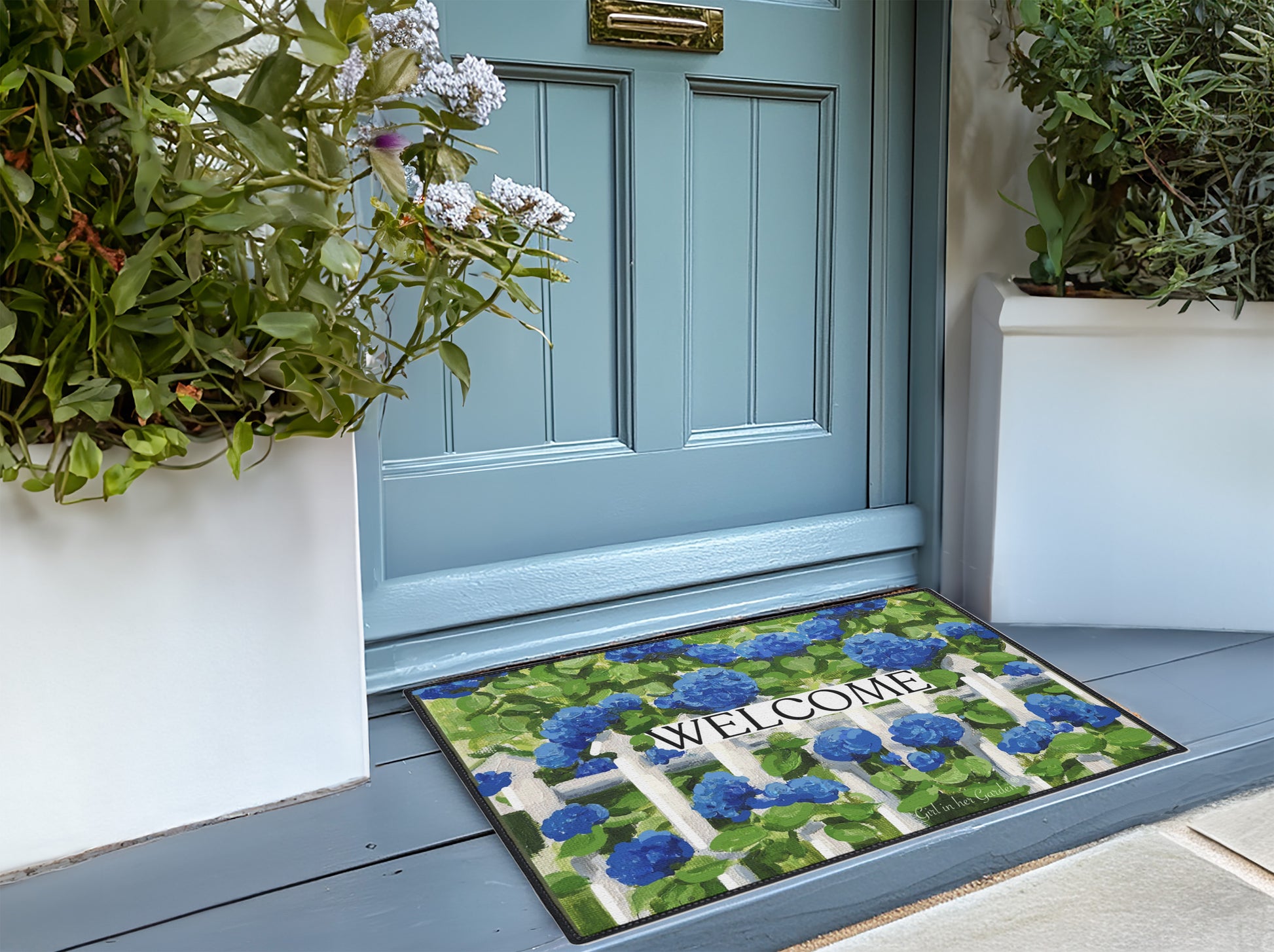 Decorative doormat with floral pattern and 'Welcome' text in front of a blue door.
