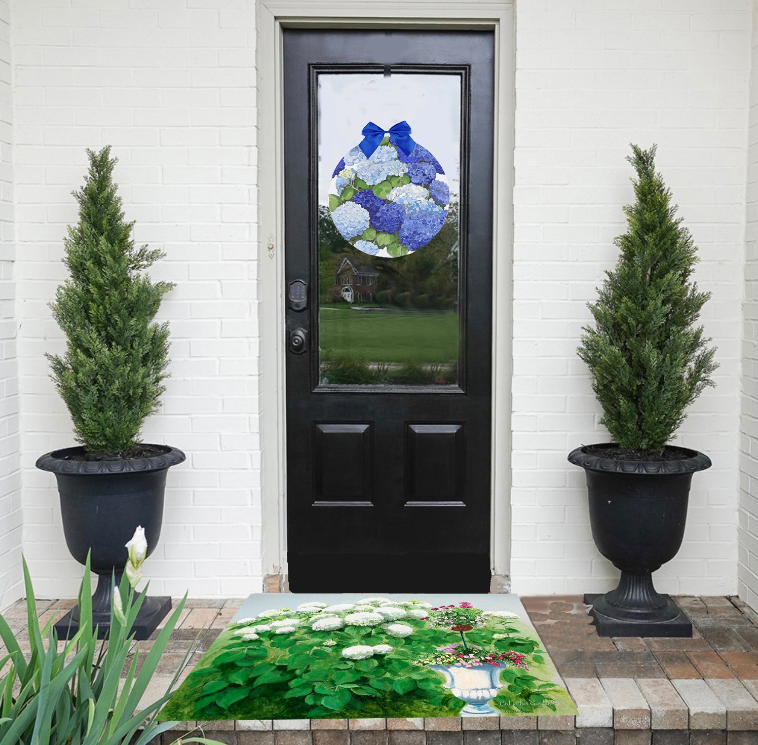 Decorative door mat with floral design in front of a black door with a decorative glass panel.