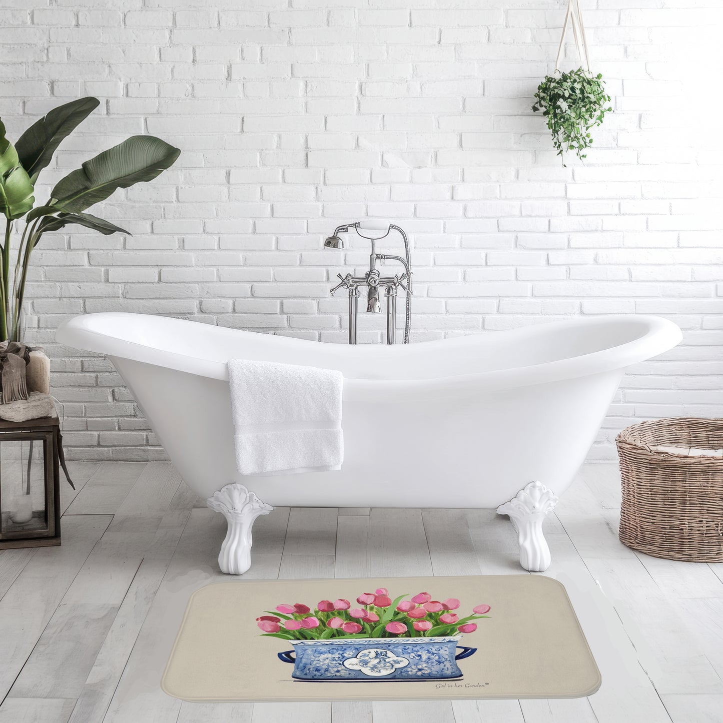 Bathroom with a white bathtub, rug with floral design, and plants.