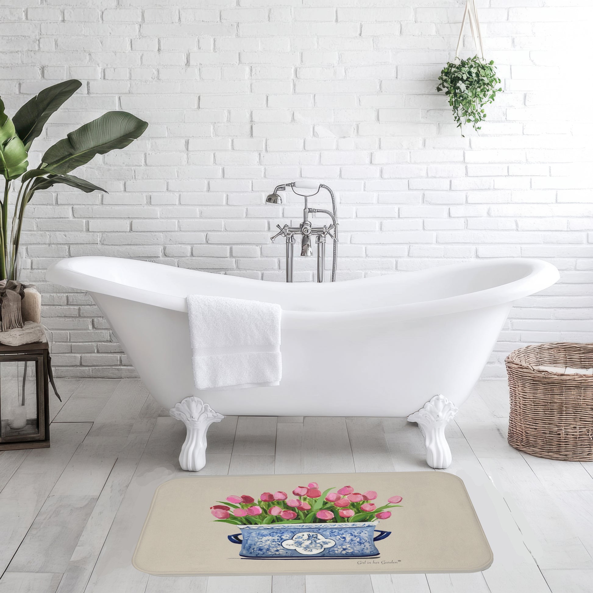 Bathroom with a white bathtub, rug with floral design, and plants.