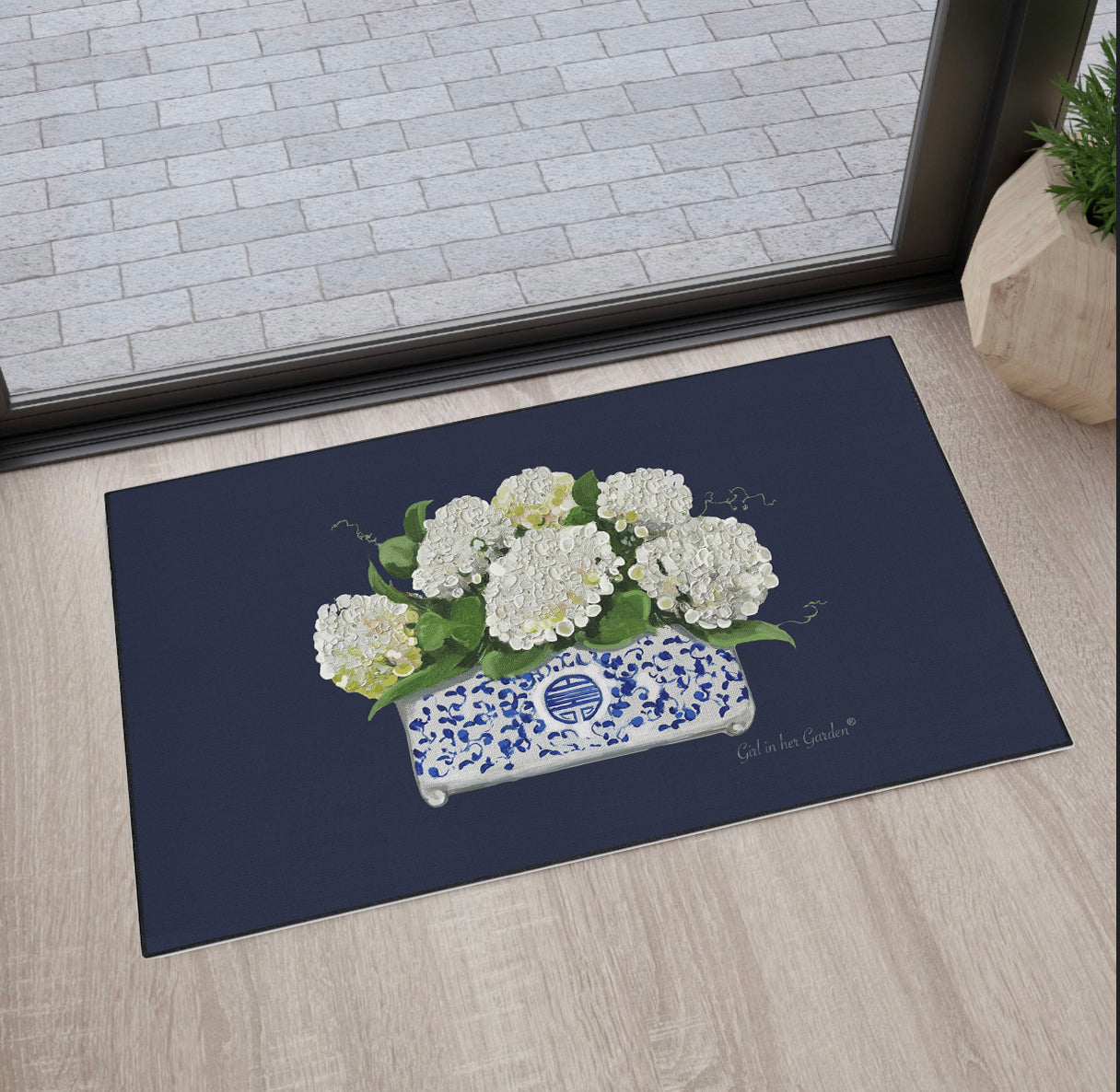 Decorative doormat with white flowers and a blue pot on a dark background