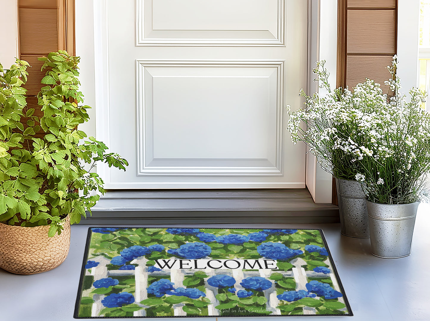 Decorative doormat with floral design and 'Welcome' text in front of a white door.