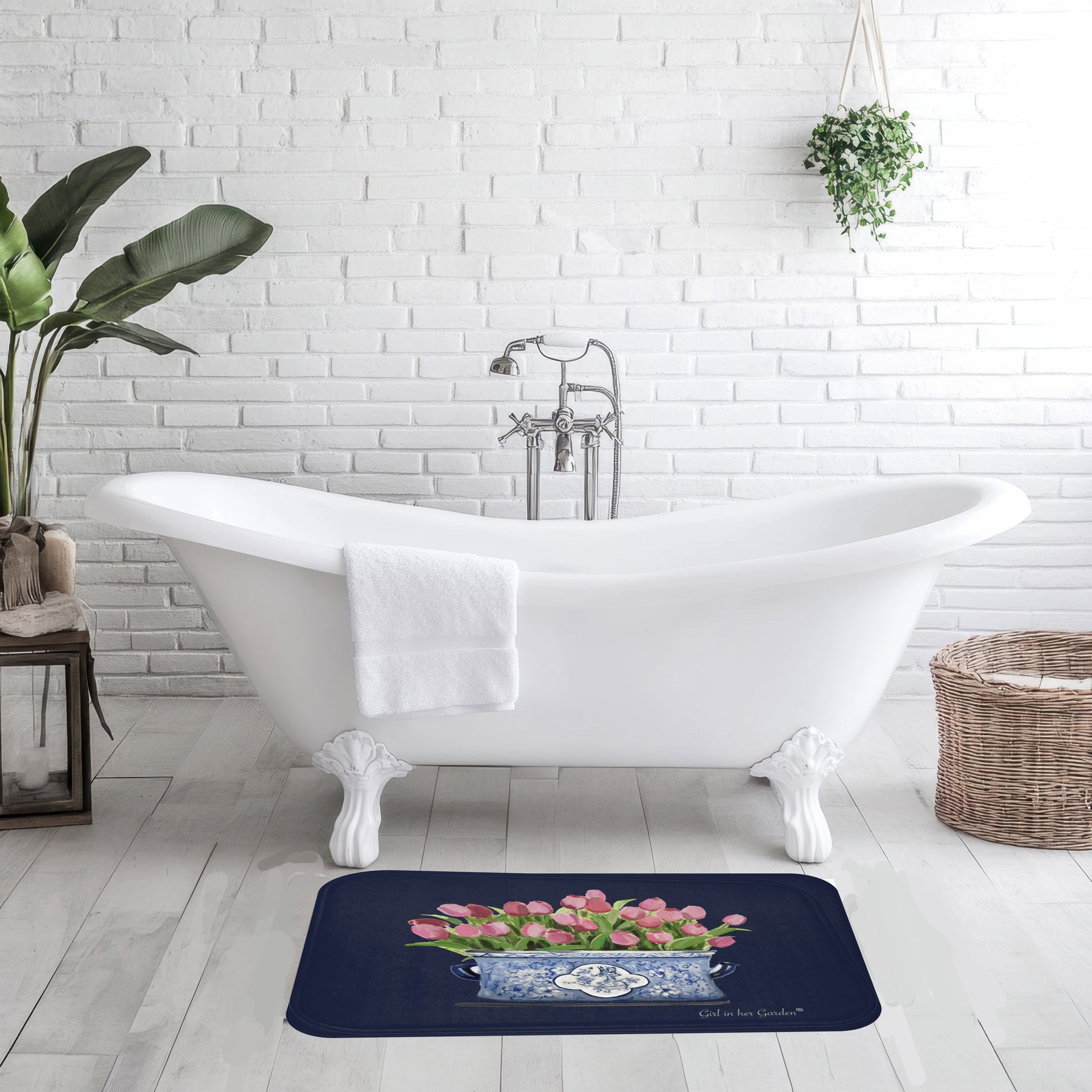 Bath mat with floral design in front of a white freestanding bathtub in a bathroom.