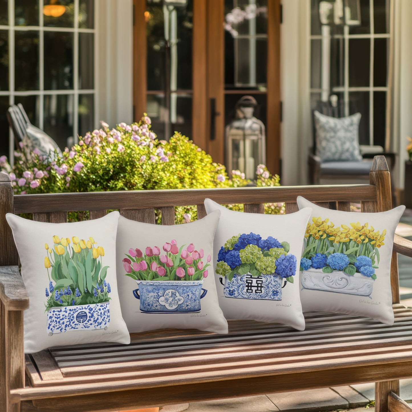 Four decorative pillows with floral designs on a wooden bench outdoors.