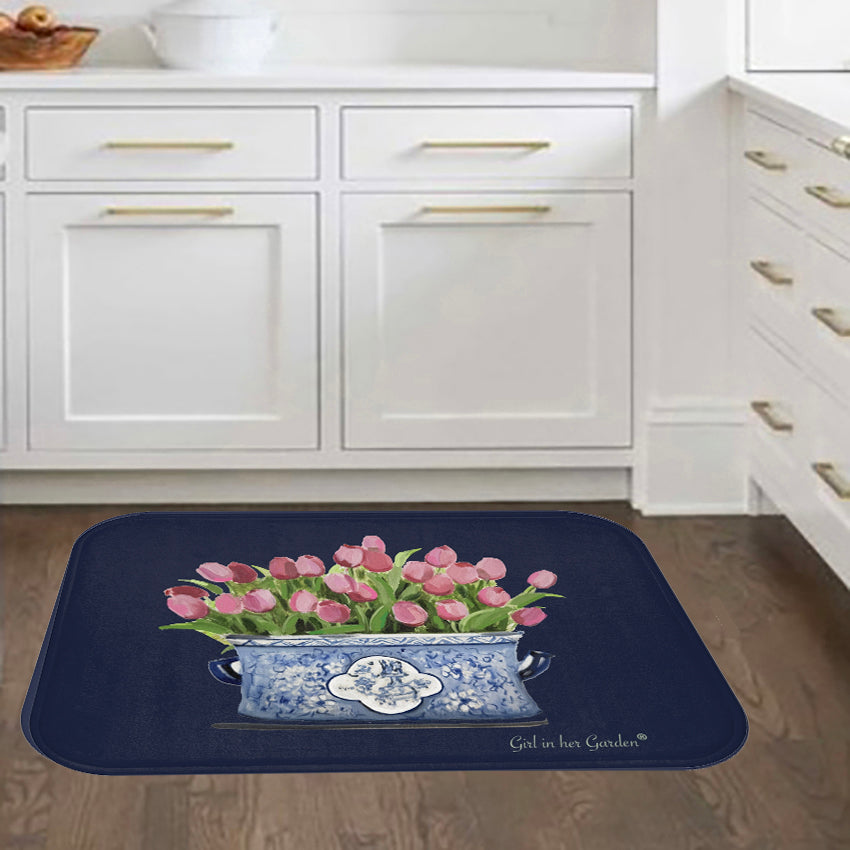 Decorative mat with pink tulips design in a blue and white container on a kitchen floor.