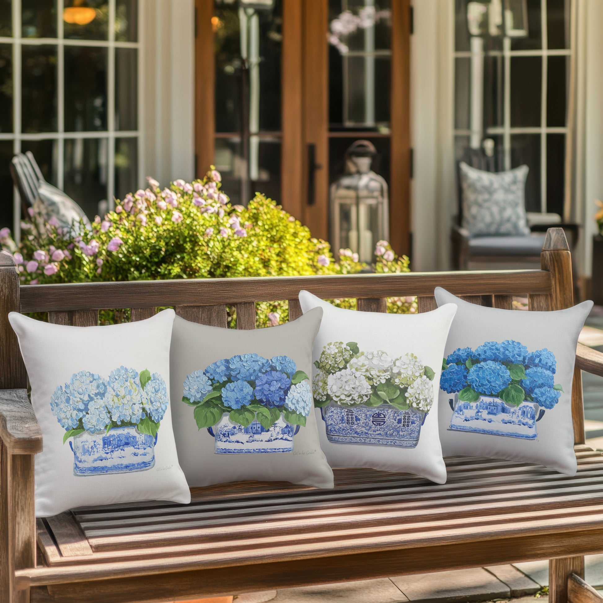 Four decorative pillows with floral patterns on a wooden bench outdoors.